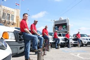 Emtec Pest Control Tulsa Workers in red shirts stand in front of service vehicles