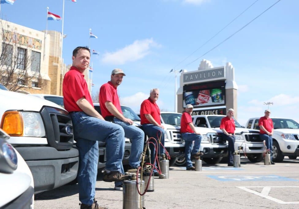 Emtec Pest Control Tulsa Workers in red shirts stand in front of service vehicles