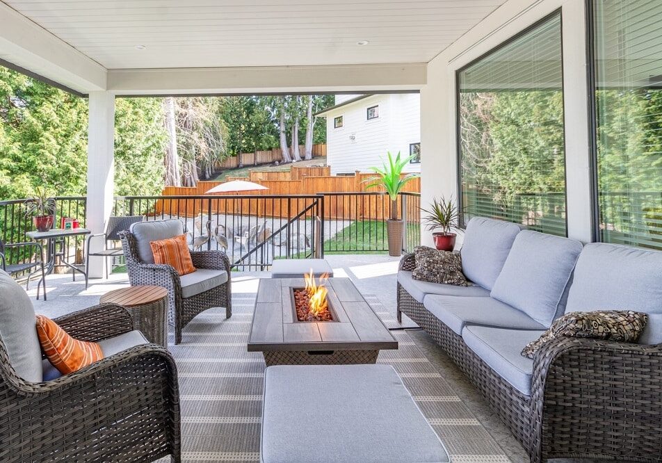A luxurious spacious deck with stylish patio furniture with a fire pit table heater