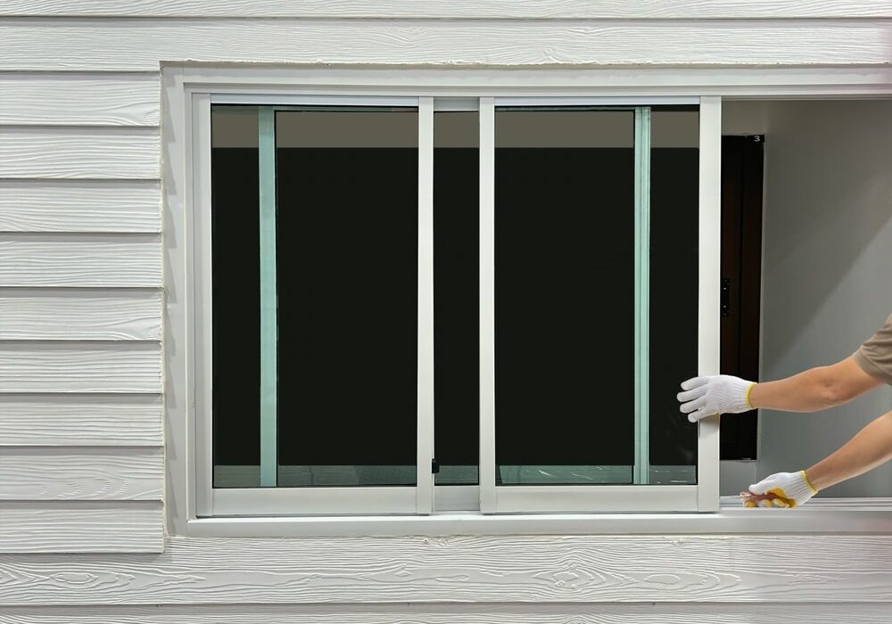 Construction worker repairing the sliding window on artificial woods siding.