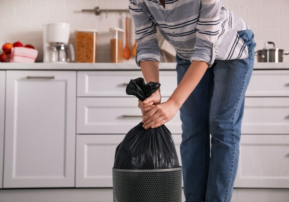 Woman taking garbage bag out of bin at home
