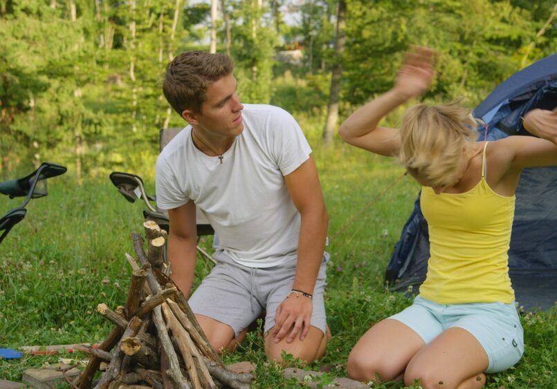 girl waves her arms as she gets attacked by a bee while preparing firewood