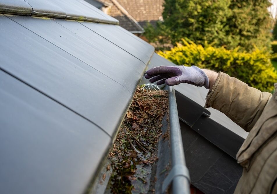 Man cleaning the blocked rain gutter