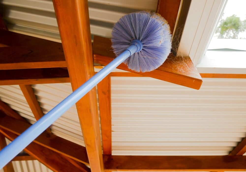 Cobweb brush sweeping spiderweb under the roof