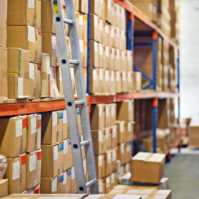 Boxes, ladder and shelves with inventory at warehouse