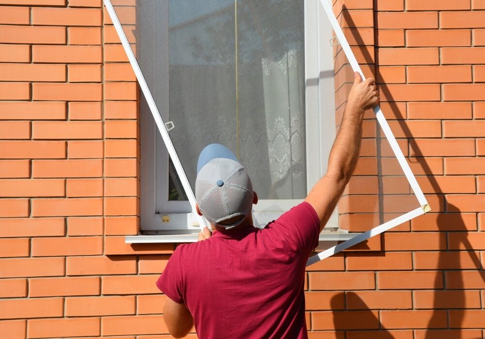 A worker is installing a window mosquito net, fly screen or insects screen to protect the house